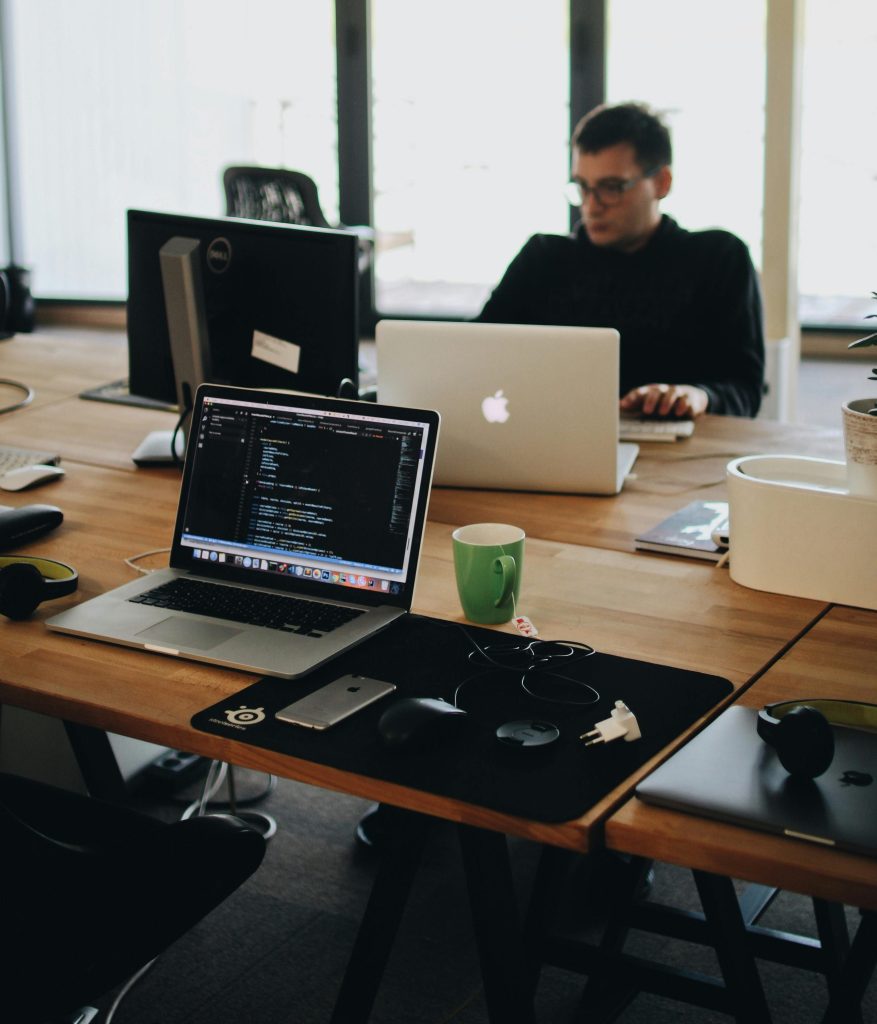 A web developer working on code in a modern office setting with multiple devices.